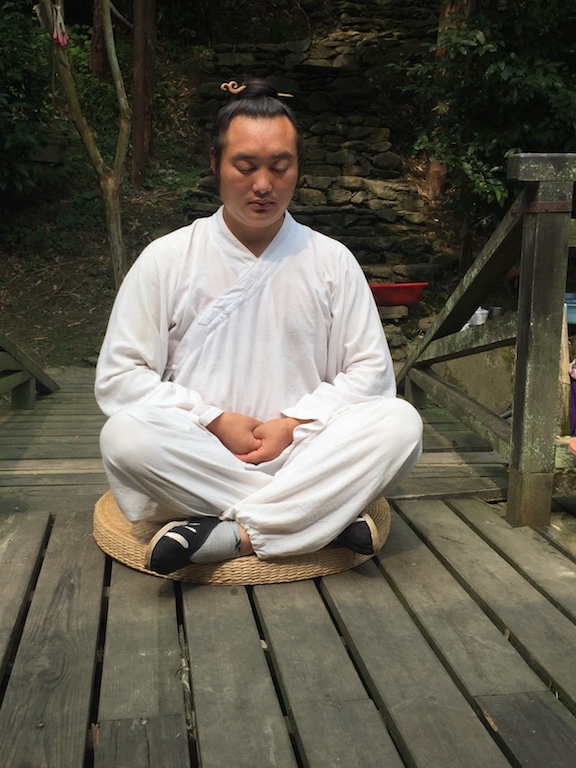 Ma^tre Ming Yue assis en tailleur